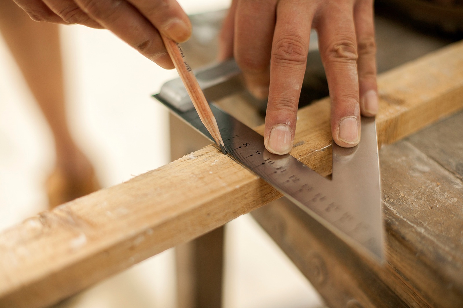 Craftsperson measuring and marking a wood strip.